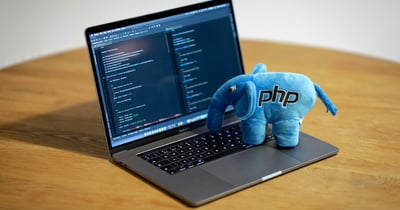 The blue PHP elephant plush toy sitting on a laptop showing code, illustrating the PHP2Shell vulnerability
